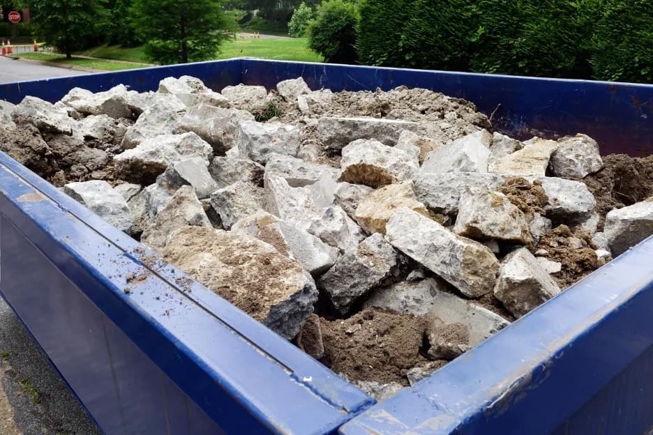 Roll-off dumpster filled with broken concrete and demolition rubble at a New York jobsite