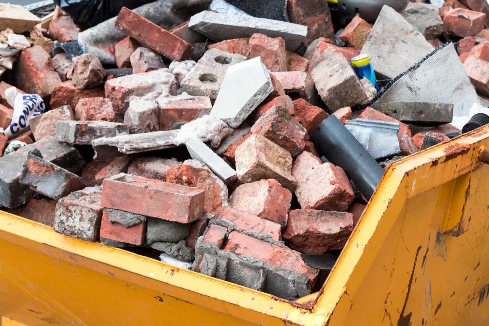 Dumpster loaded with concrete, brick, and heavy masonry fill during a construction teardown