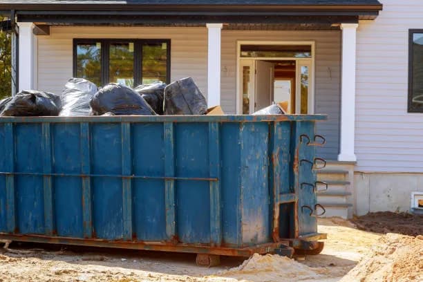Full roll-off dumpster on a residential driveway during a home cleanout