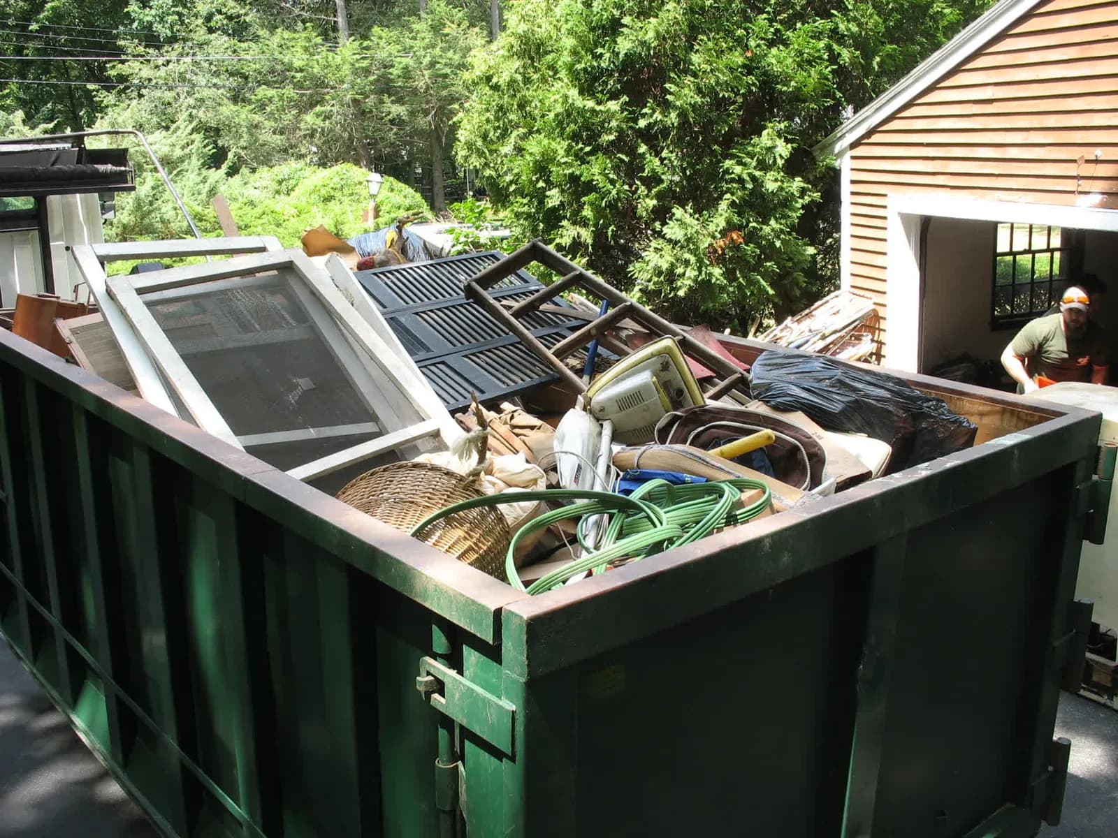 Dumpster packed with cardboard, furniture, and household junk during a cleanout