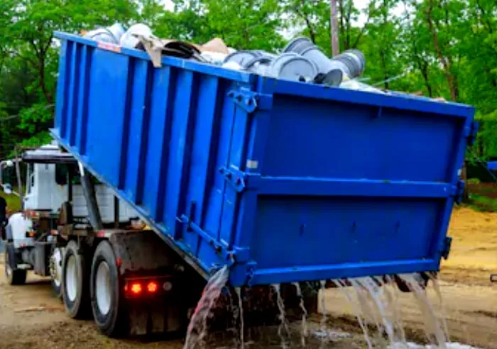 Green roll-off dumpster on a front lawn holding renovation and remodel debris