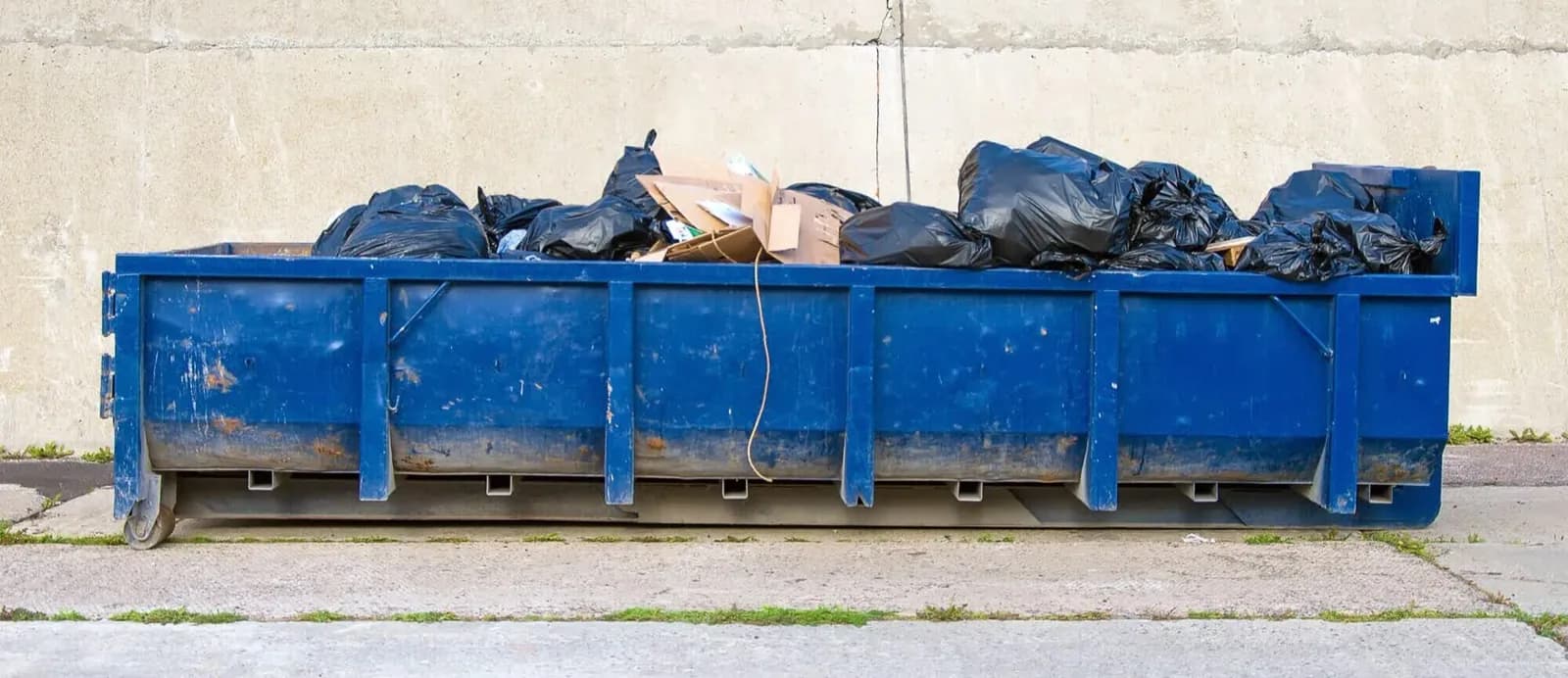 Roll-off dumpster loaded onto a hauler truck at a commercial cleanout