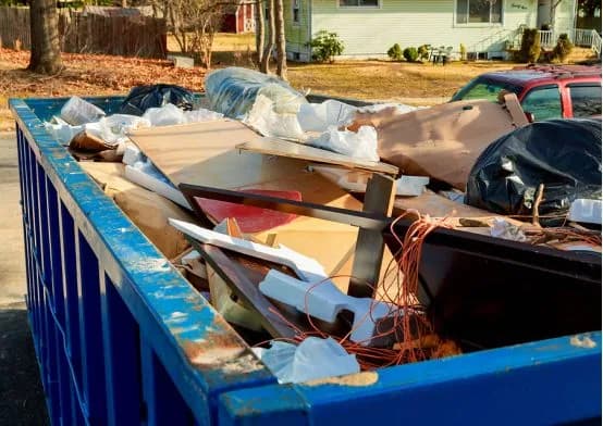 Roll-off dumpster on a flatbed being delivered to a busy jobsite