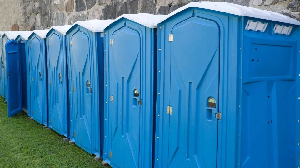 Clean portable restrooms delivered and staged along a construction jobsite fence