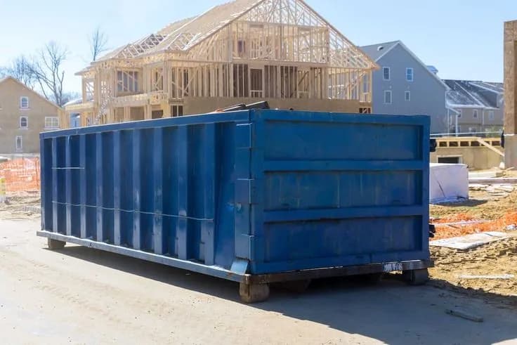 Blue roll-off dumpster with the door open, staged for heavy loading