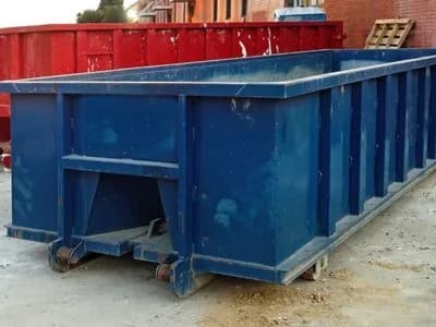 Empty green roll-off container dropped at a commercial site before a cleanout