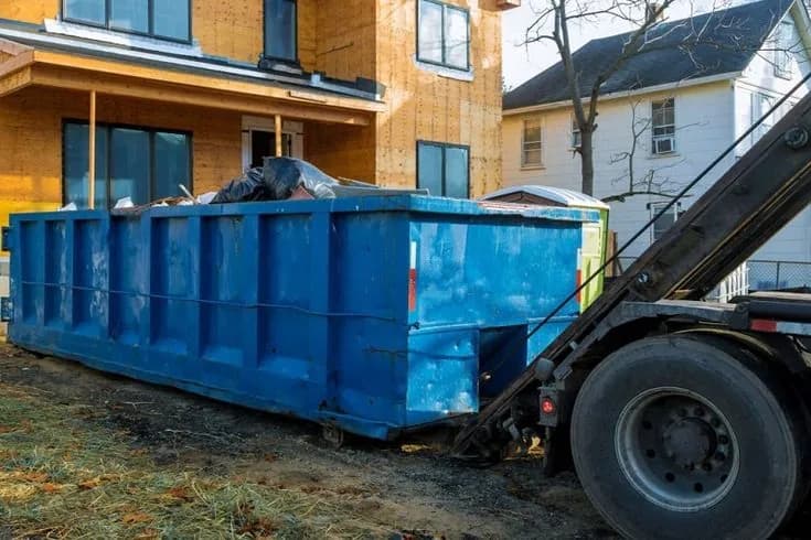 Red roll-off dumpster staged in a driveway with the loading door down